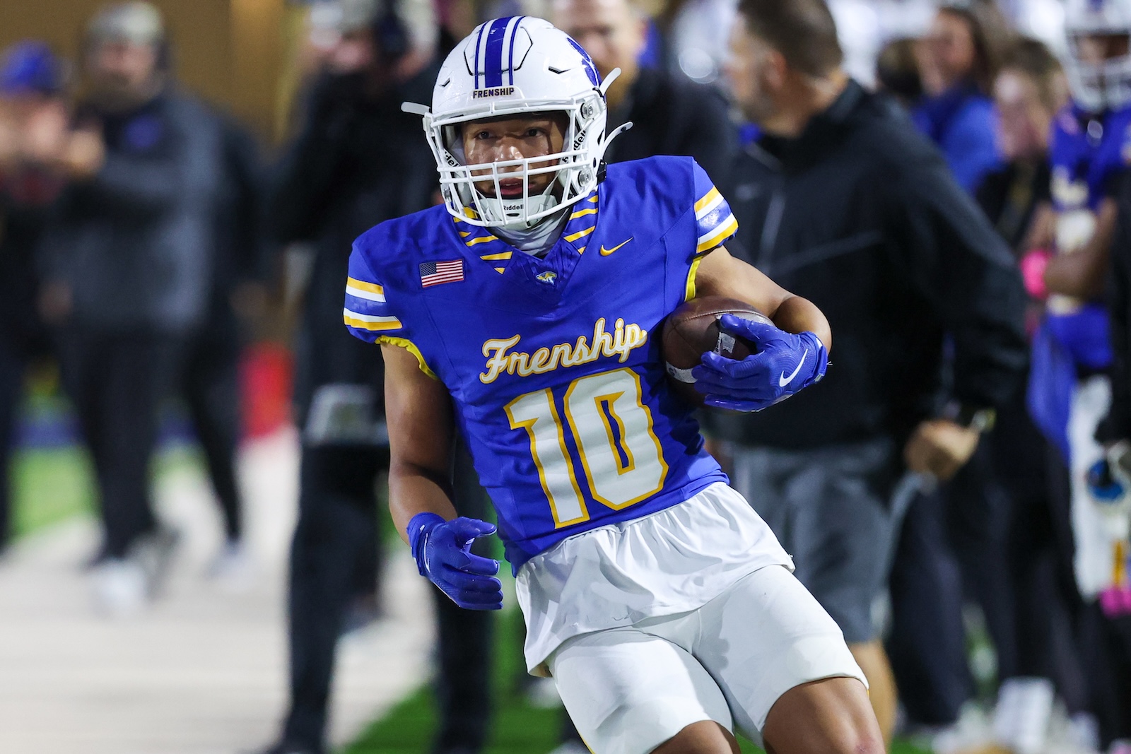 Seabolt Chase-19323 | Press Pass Sports Frenship football player wearing #10 in blue and yellow, running with the ball on the field