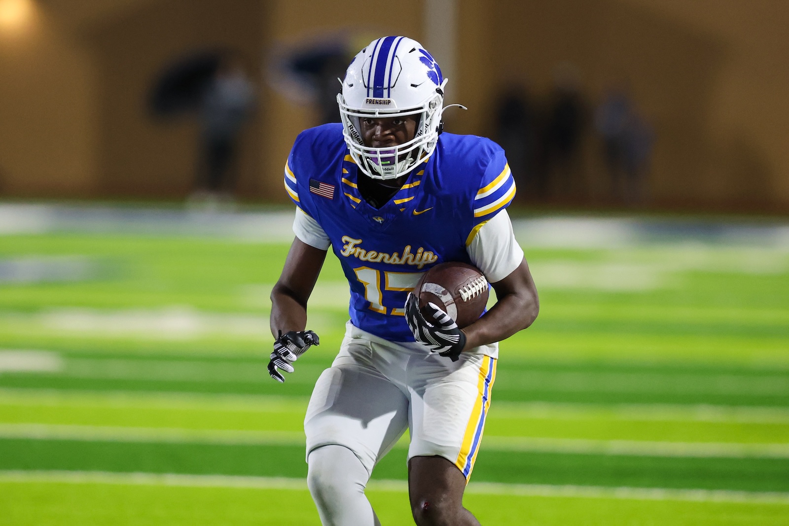 Seabolt Chase-19518 | Press Pass Sports American football player in a blue and yellow jersey sprinting with the ball on a green field, helmet on, during a game.